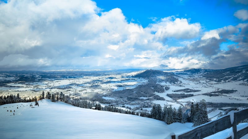 Snowy hills and forest under a cloudy sky