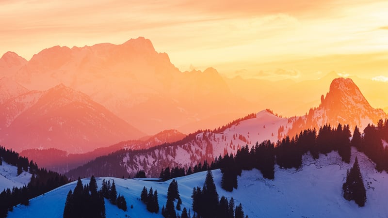 Snow-covered mountains under an orange sky