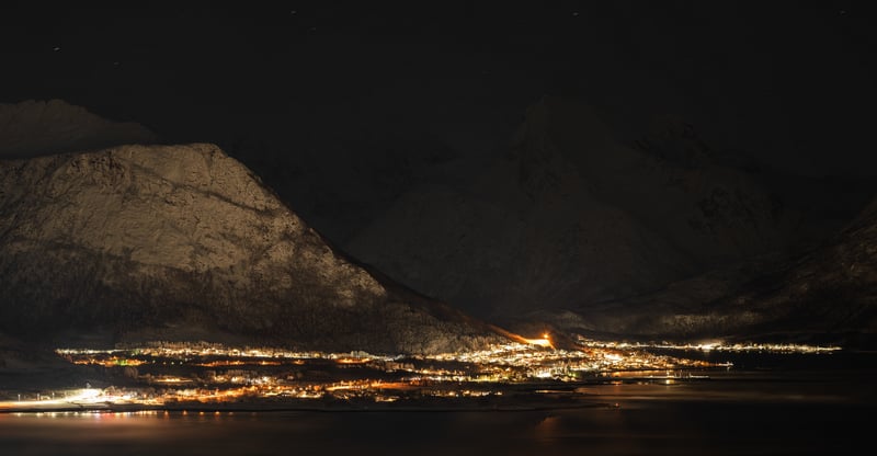 Town lights at night with snowy mountains