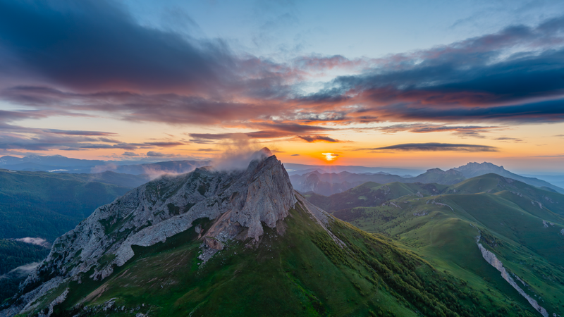 Sunrise over a rocky mountain range with clouds