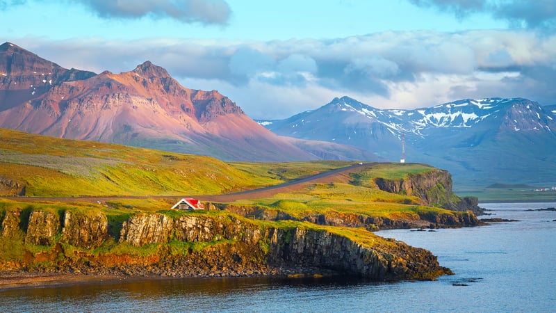 Coastal landscape with mountains and a small house