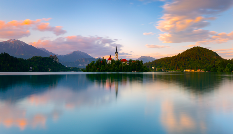 Lake with Island Church and Mountains at Sunset