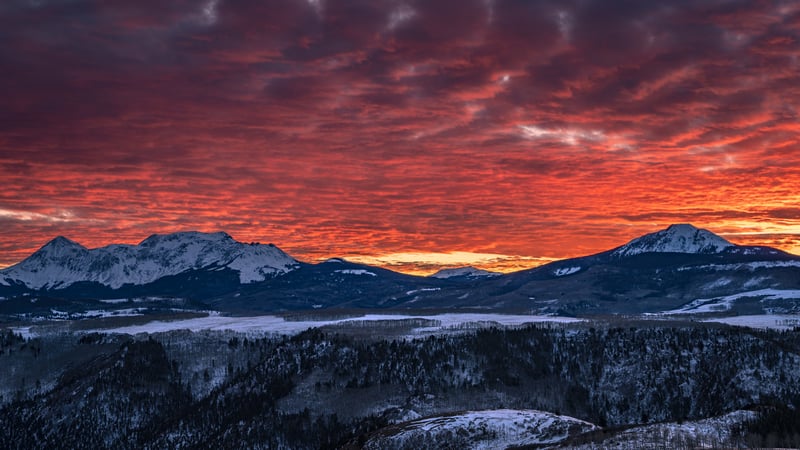 Fiery sunset over snow-covered mountains and forest