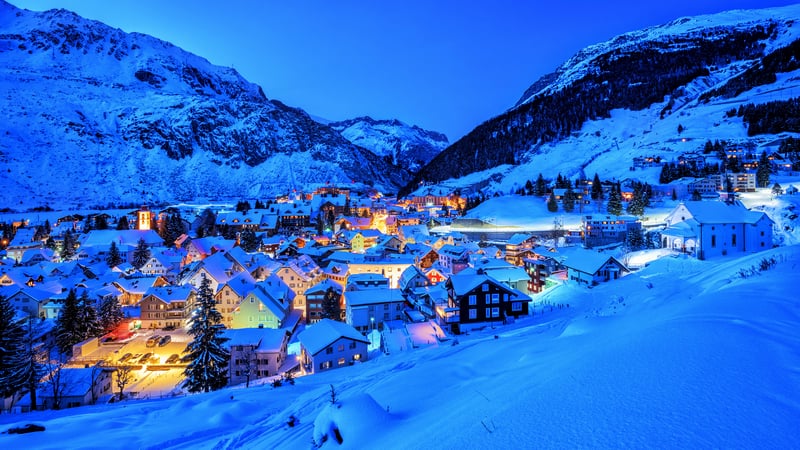 Snowy mountain village at dusk with illuminated houses