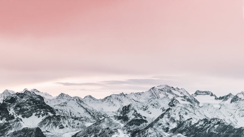 Scenery of snow-covered mountains under a pink sky