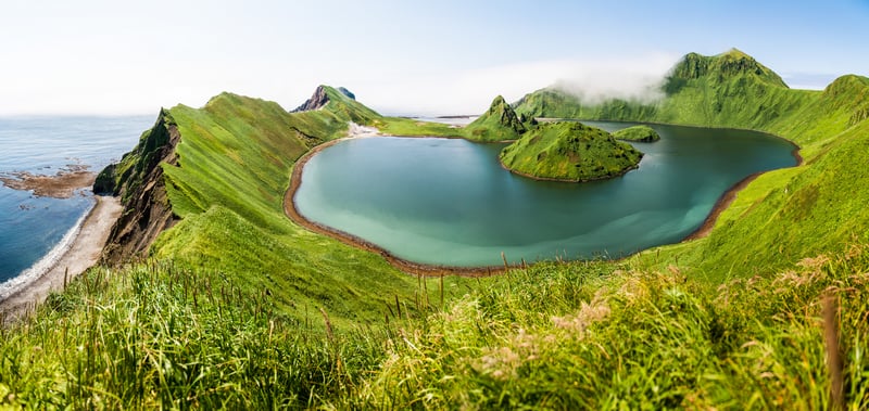 Green island with a lake and misty mountains