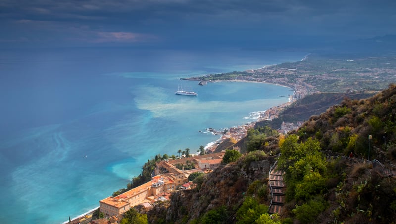 Cruise ship in a bay with a coastal town and mountains