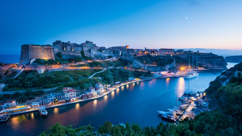 Boat docked in a harbor with a town on a hill