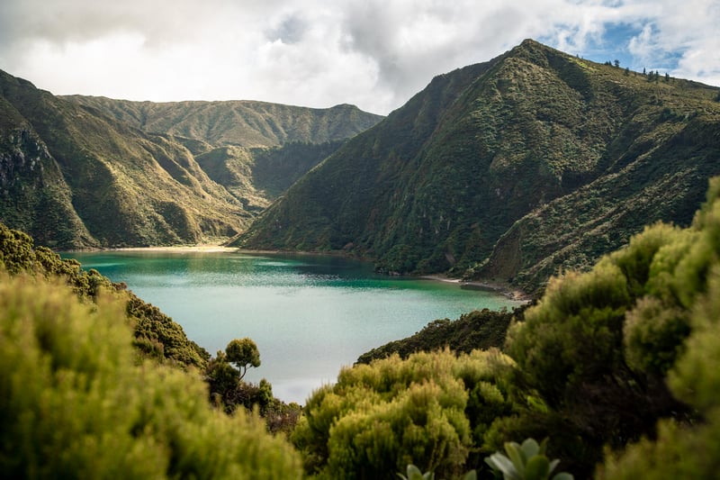 Volcanic lake surrounded by green hills under clouds