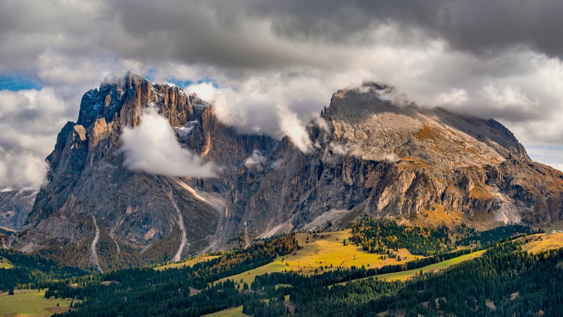 Rocky mountains with clouds and autumn trees