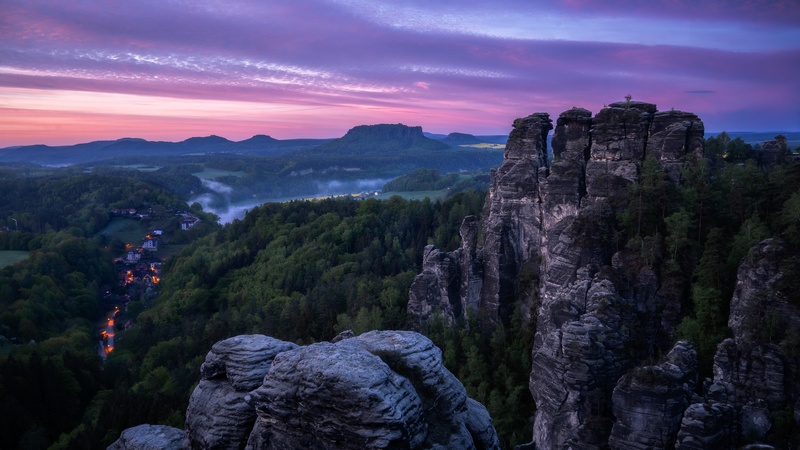 Rocky peaks and village at sunrise with purple sky
