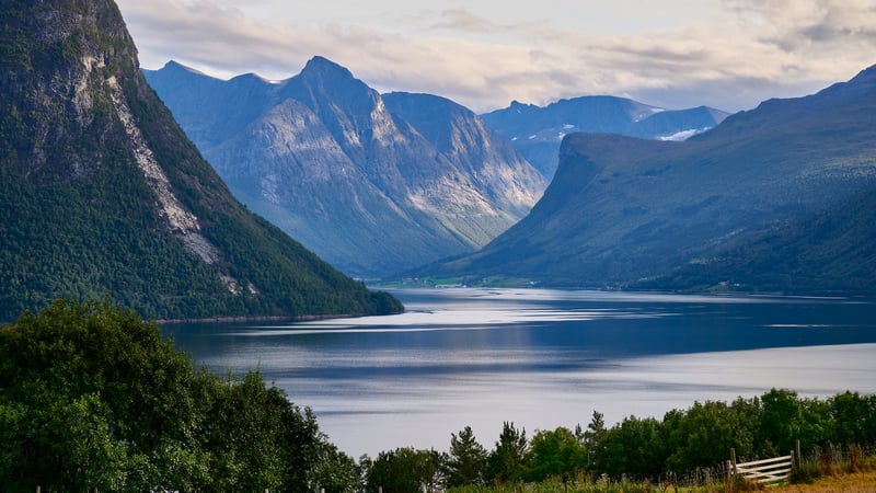 Calm lake surrounded by majestic mountains under a cloudy sky