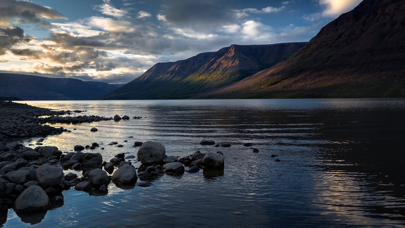 Mountain lake with rocky shore and dramatic clouds