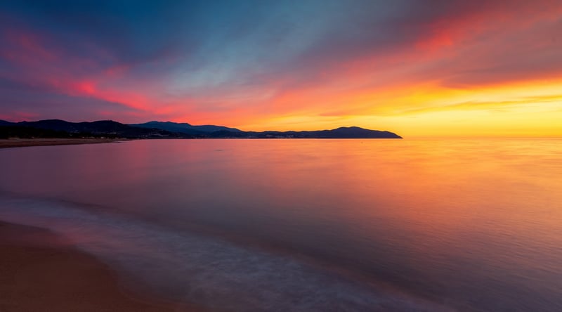 Sunset over the ocean with mountains in the distance