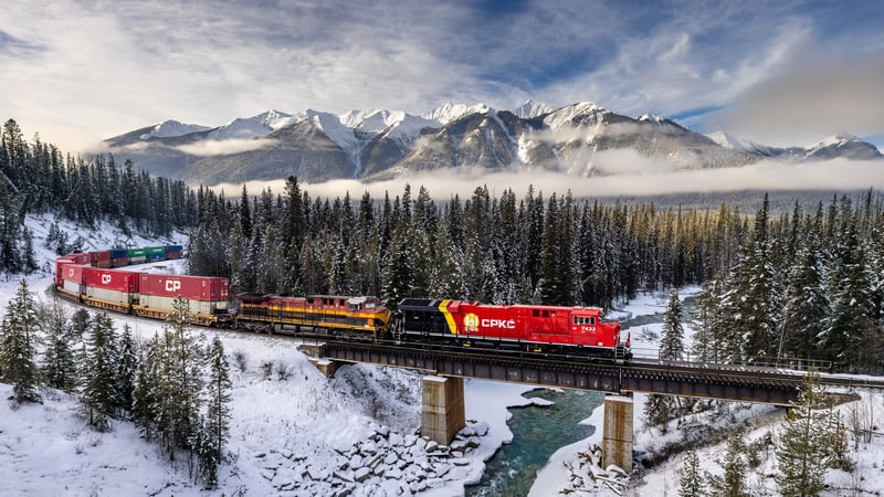 Train crossing a bridge in a snowy mountain landscape