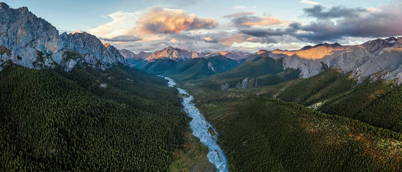 River flowing through a forested mountain valley at sunset