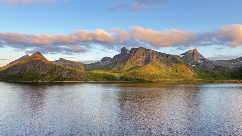 Mountains reflected in a calm body of water under a cloudy sky