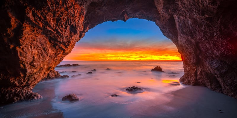 Cave entrance overlooking ocean at sunset with long exposure