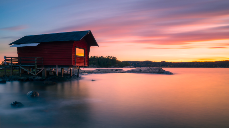 Red cabin on stilts by the water at sunset