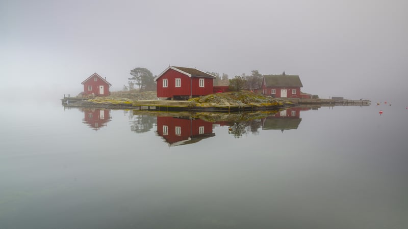 Red houses on a misty island with water reflection