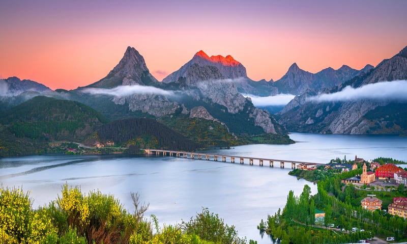Mountains over a lake with a bridge and town