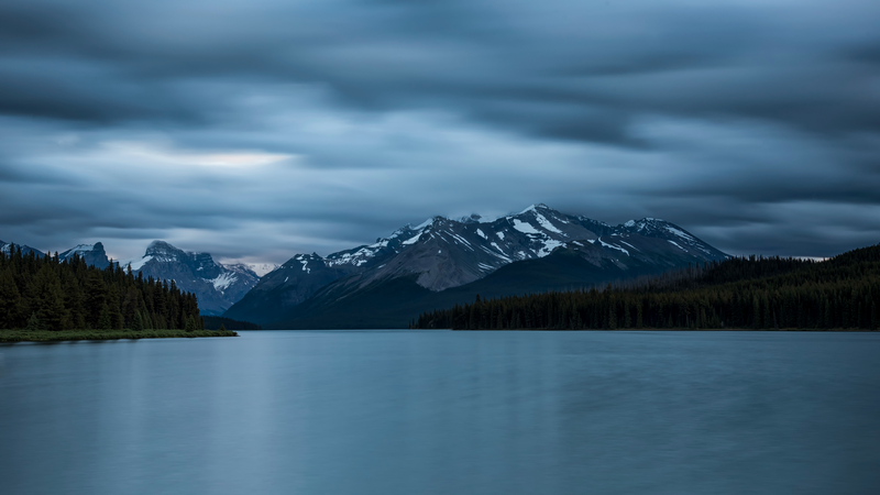 Lake and snow-capped mountains under cloudy sky