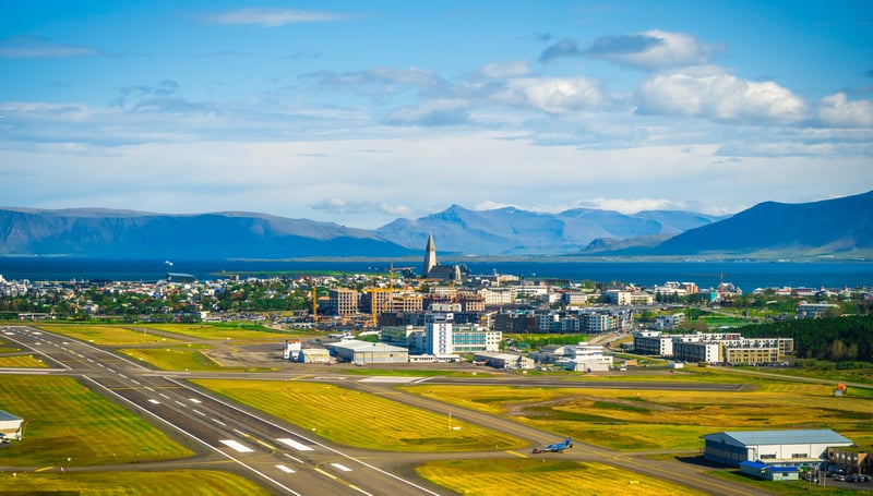 Aircraft on a runway with a city and mountains in the background