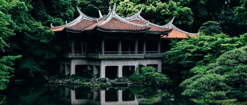 Asian architecture building reflected in water surrounded by trees