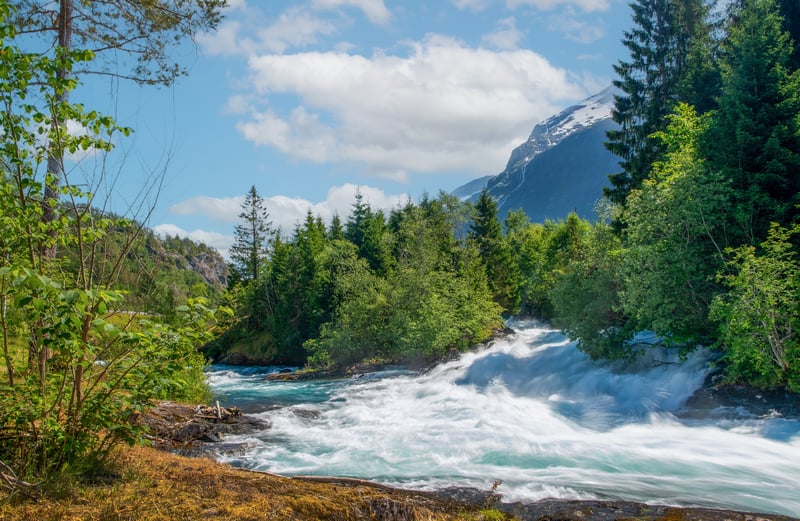 Fast flowing river in Norway with mountains and trees