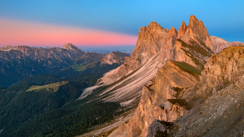 Jagged mountain peaks at sunrise with forest below