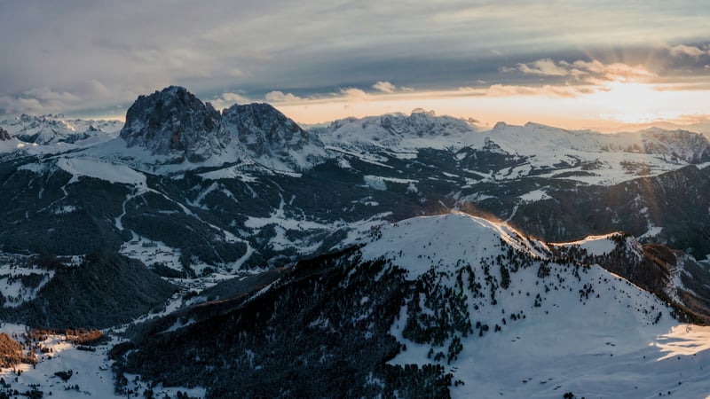 Snowy mountain peaks at sunset with clouds