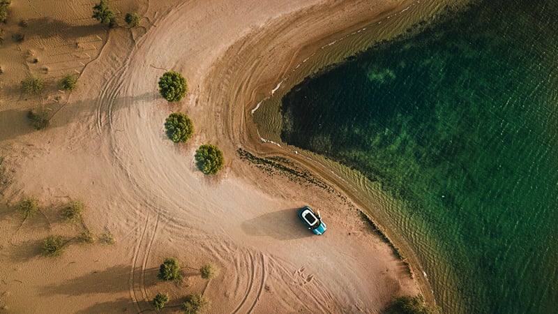 Blue Mini Cooper Countryman on a sandy beach by the water