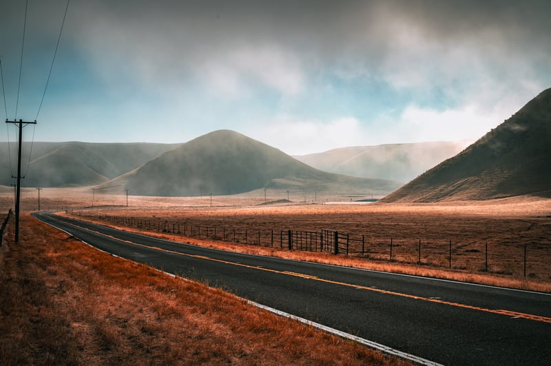 Empty country road through rolling hills and fog