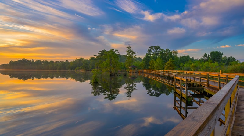 Wooden boardwalk over a calm lake at sunrise
