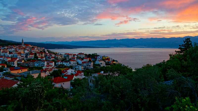 Coastal town at sunset with mountains in the background