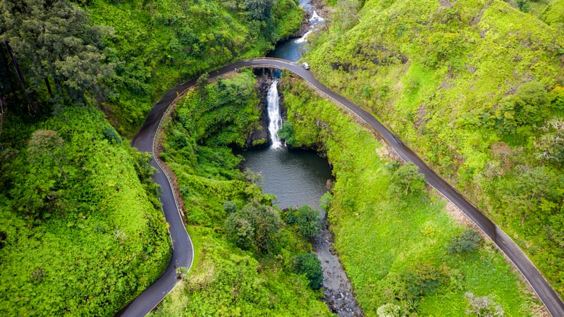 Car on a winding road near a waterfall