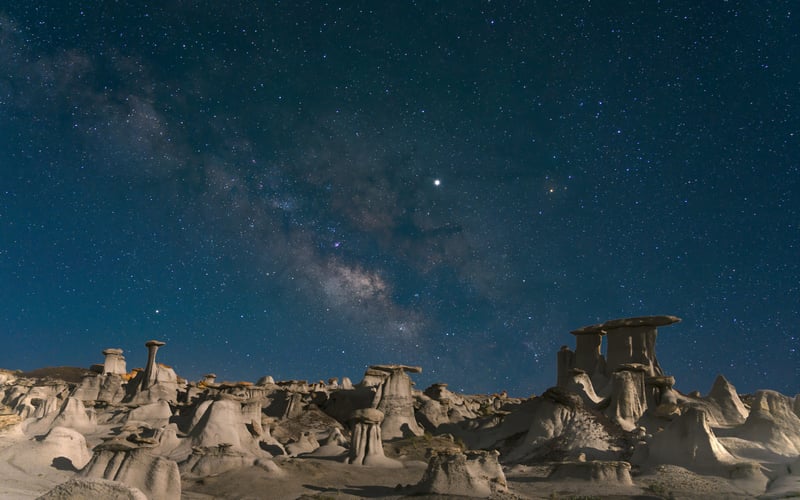 Starry night sky over desert rock formations