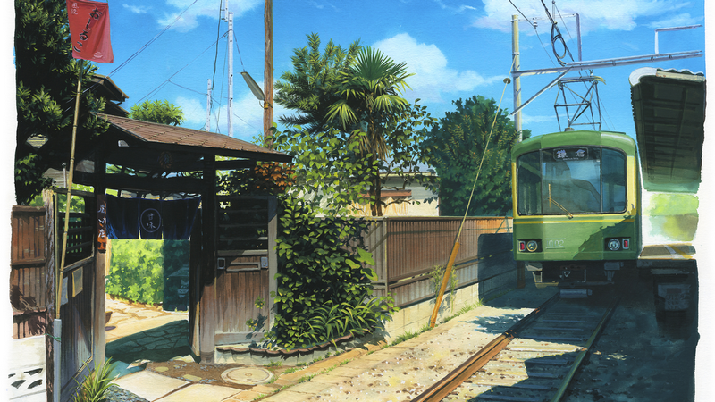 Green train at a Japanese railway station with traditional architecture