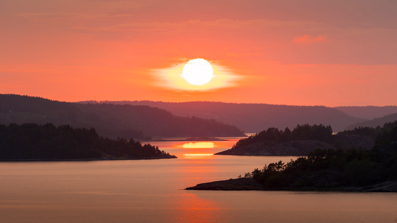 Sunset over a calm sea with islands and trees