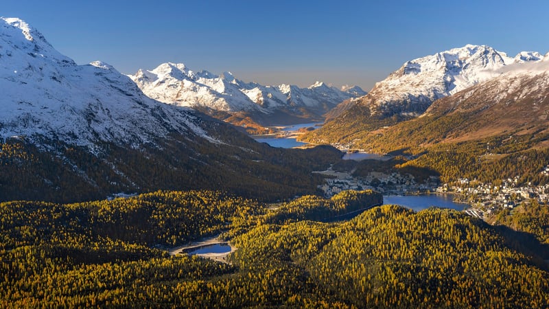 Snow-capped mountains and golden forest surround lakes