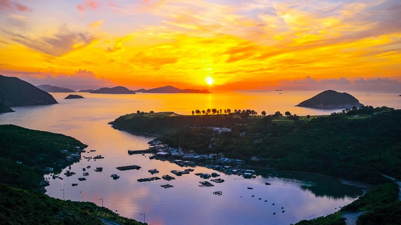 Boats in a bay at sunset with islands