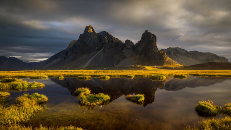 Mountain reflection in water with grass and clouds
