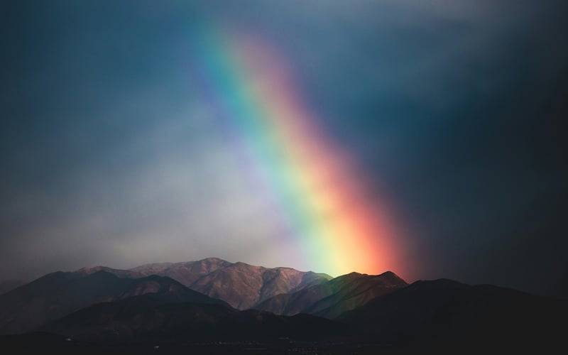 Rainbow over dark mountains at twilight