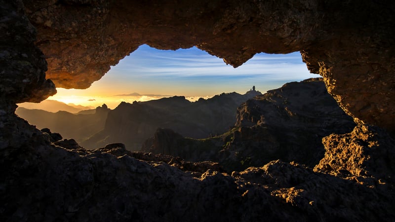 Cave opening framing sunset over Gran Canaria mountains