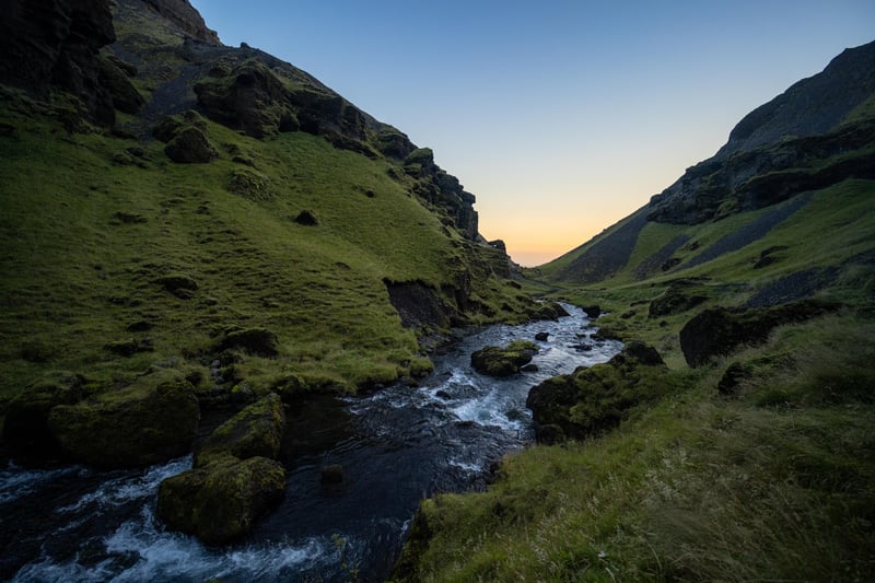 River flowing through a green valley at sunset