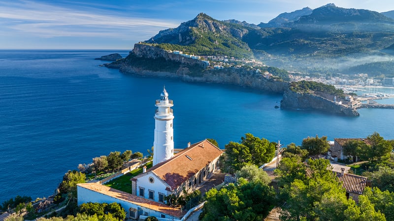 Lighthouse on a cliff overlooking the sea with mountains