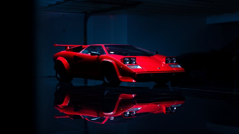 Red Lamborghini Countach in low light with reflection