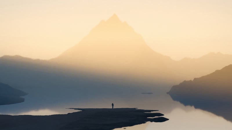 Man standing on island with mountain and lake
