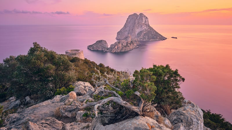 Rocky cliff overlooking Es Vedrà island at sunset