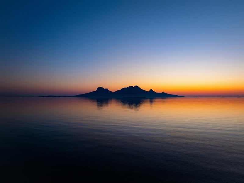 Island silhouette reflected in calm water at sunset